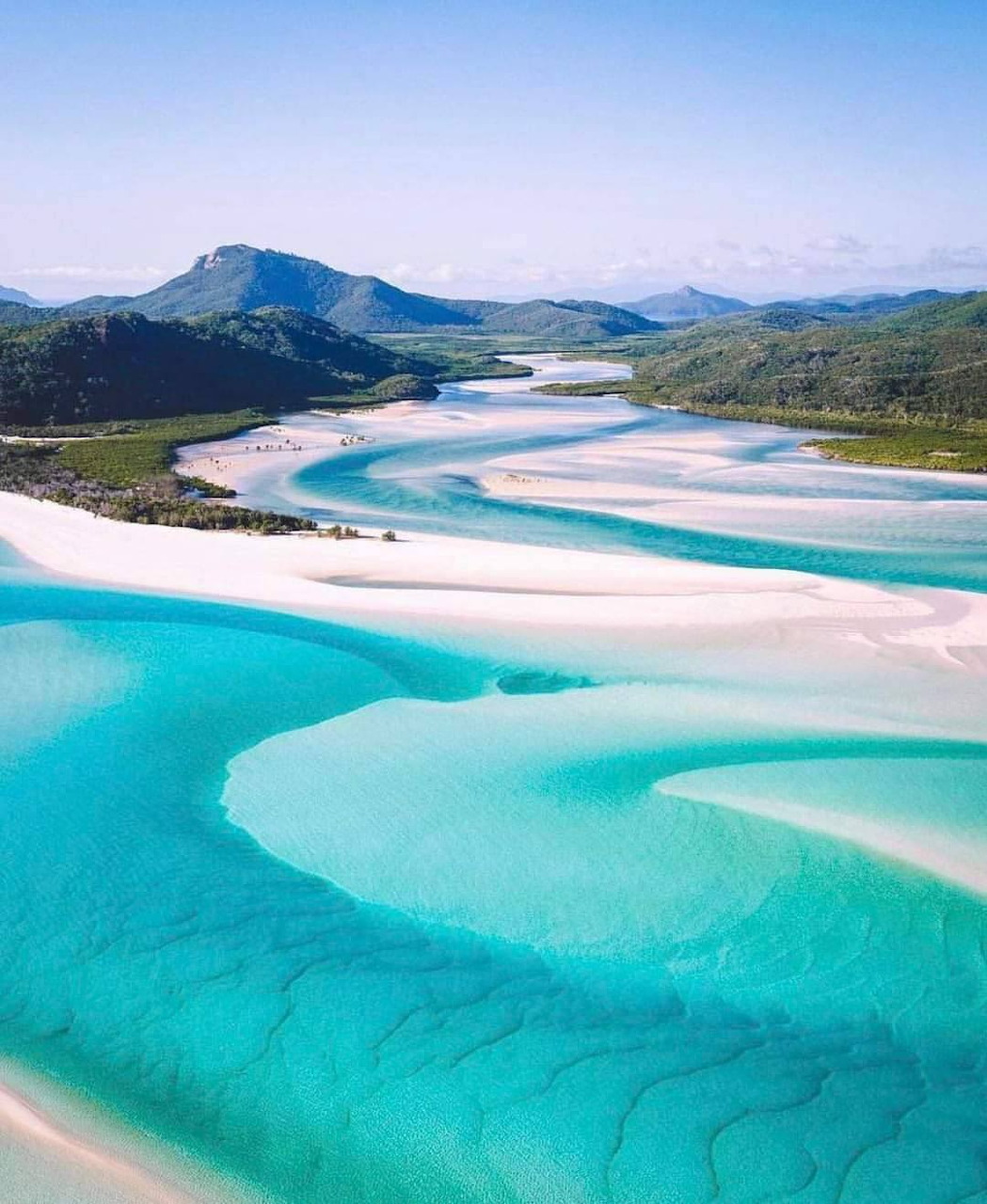 Aerial view of turquoise water and white sandbars with distant green hills