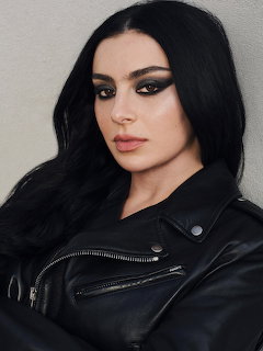Woman with long black hair and dark smoky eye makeup wearing a black leather jacket