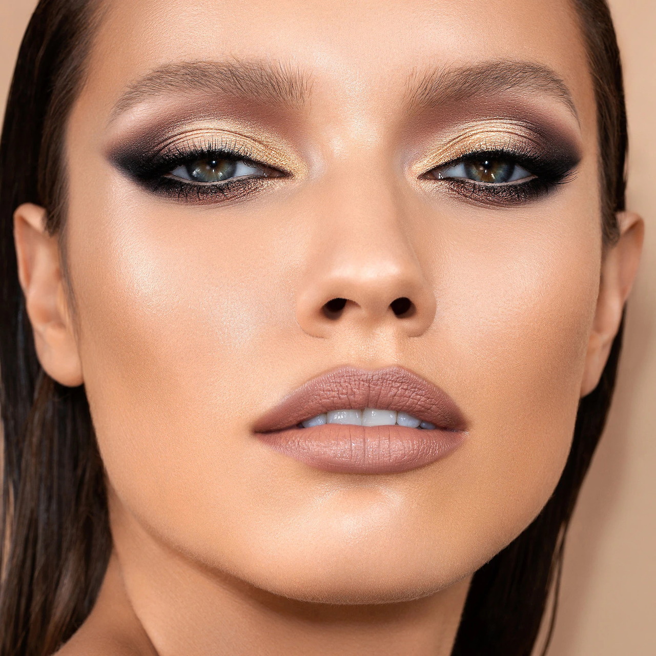 Close-up portrait of woman with dramatic bronze eye makeup and nude lips