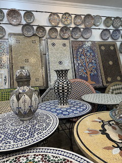 Display of Moroccan mosaic tables, ceramic plates, and traditional tiles with geometric patterns in a Fez shop