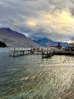 Wooden wharf on a lake with mountains and dramatic clouds, vintage steamship docked at right