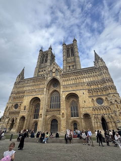 Lincoln Cathedral facade with Gothic towers and people standing in the square
