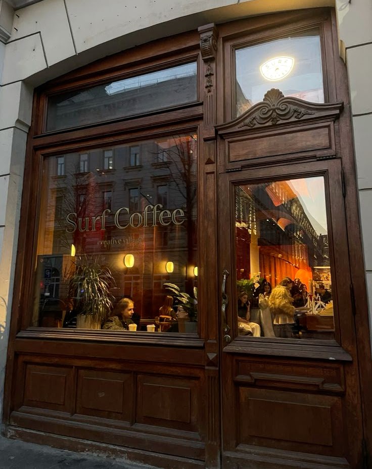 Ornate wooden coffee shop storefront with glowing windows at twilight