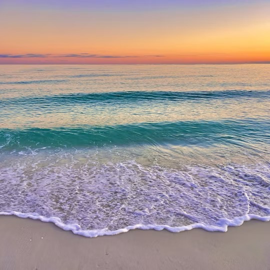 Sunset over ocean beach with colorful sky, turquoise waves, and foamy shore