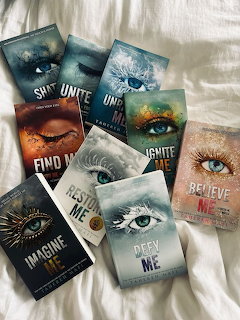 Several fantasy book covers with eye illustrations arranged on a white bedspread
