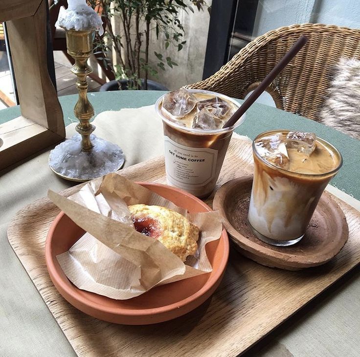 Two iced coffee drinks and a pastry on a café table by a window