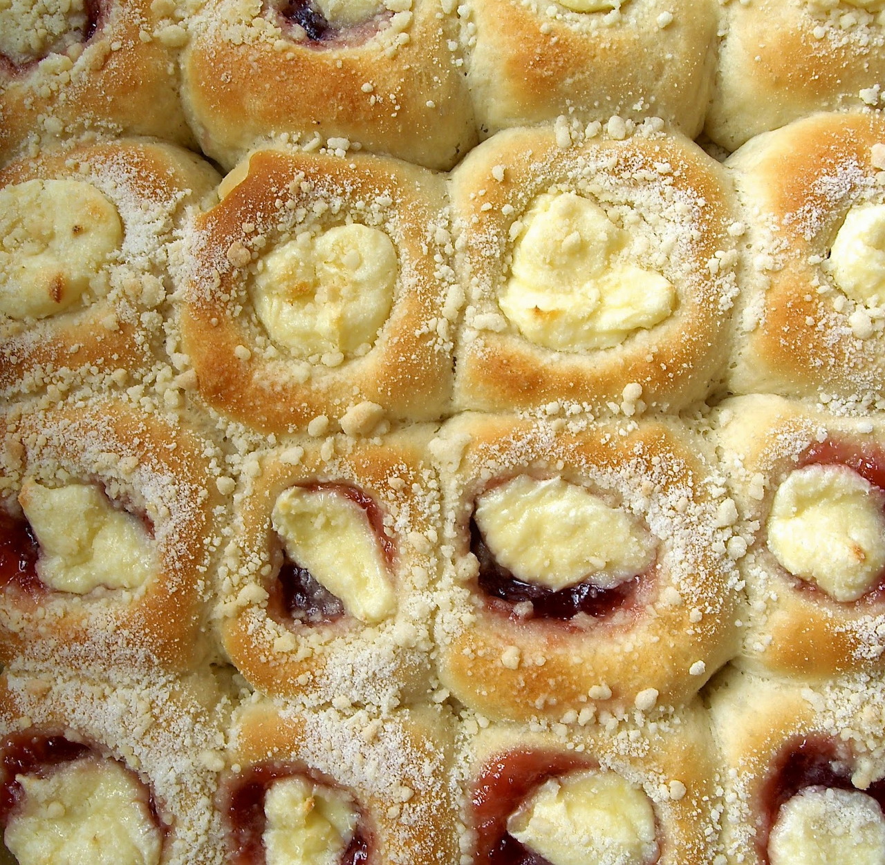 Close-up of kolaches with powdered sugar, cream cheese and fruit fillings