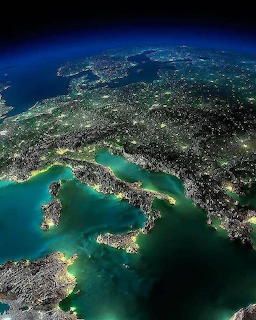 Satellite image of Europe at night showing Italy and the Mediterranean with city lights and blue atmosphere