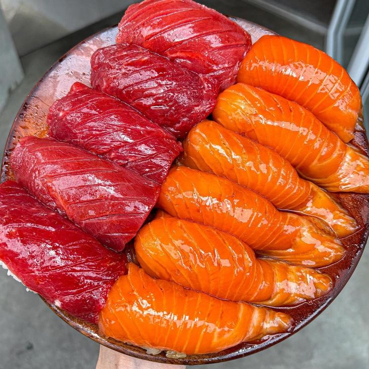 Round wooden plate with sliced raw tuna and salmon sashimi arranged in rows
