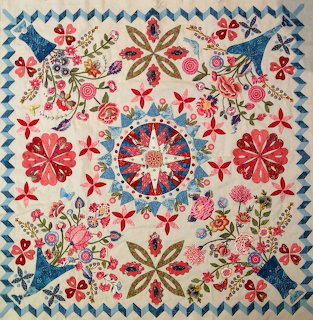 Quilt-style floral pattern with birds, flowers, and a central star design