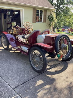 Red 1913 Ford Model T Speedster with brass trim and spoke wheels parked in driveway