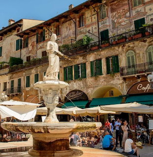 Madonna Verona fountain statue in front of frescoed historic buildings in Piazza delle Erbe, Verona