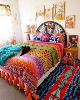 Bright bohemian bedroom with multicolored quilt, rattan headboard, wall art, and black cat resting on bed