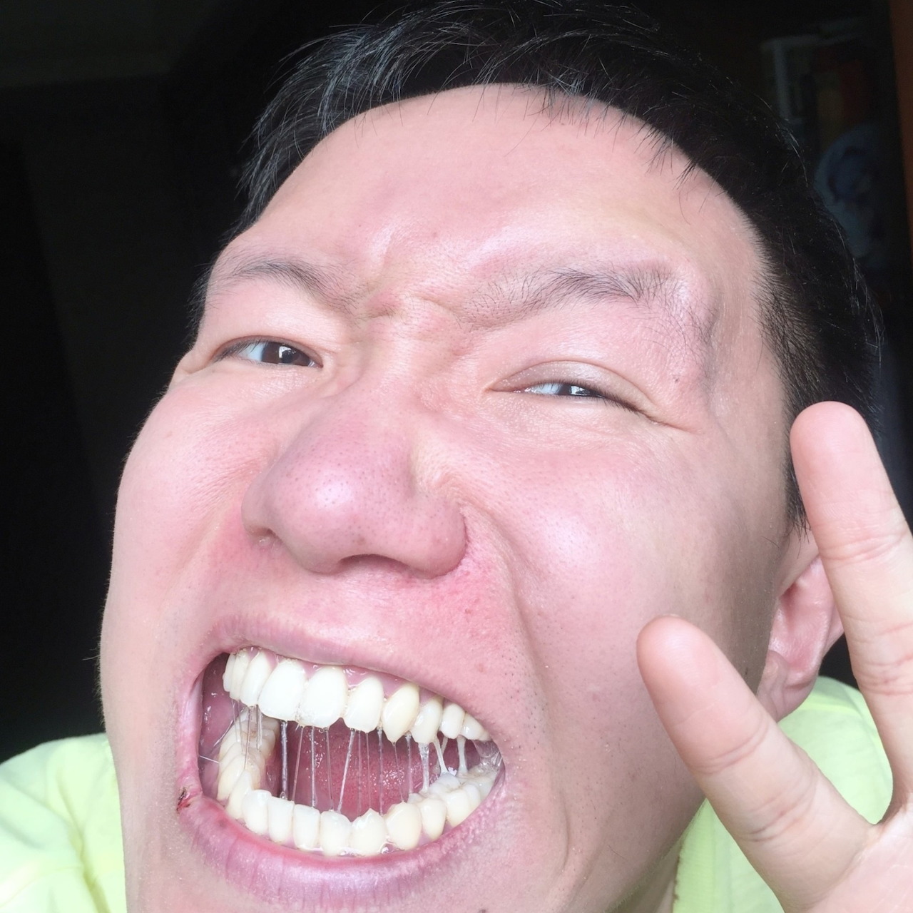 Close-up selfie of a man grinning widely and holding up a peace sign