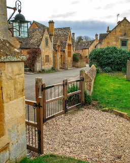Traditional Cotswold village street with stone cottages and wooden gate