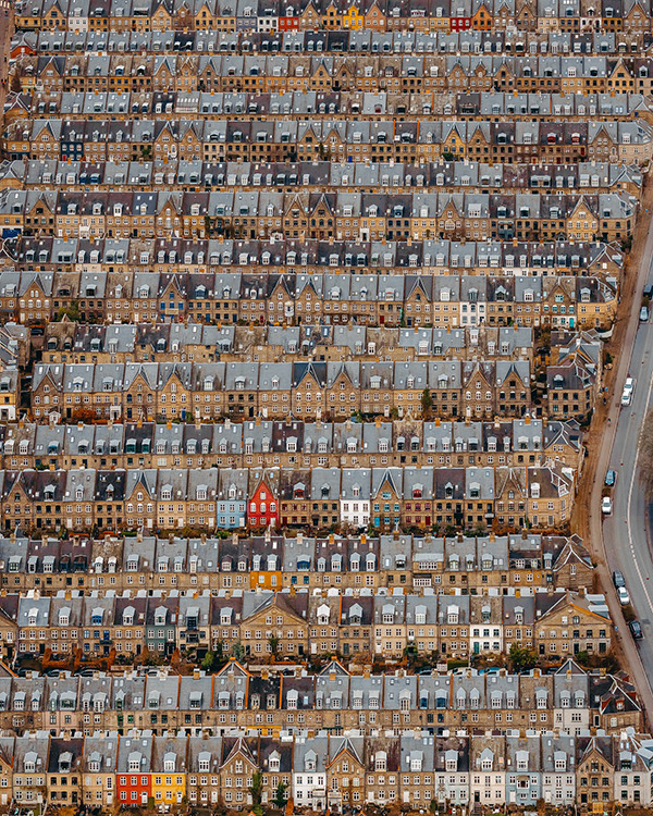 Aerial view of densely packed rows of terraced houses with uniform grey and brown rooftops