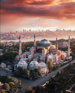 Aerial view of Hagia Sophia mosque with domes and minarets at sunset, Istanbul skyline and Bosphorus behind