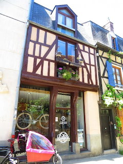 Half-timbered medieval building with shop front and flower boxes in Bourges, France
