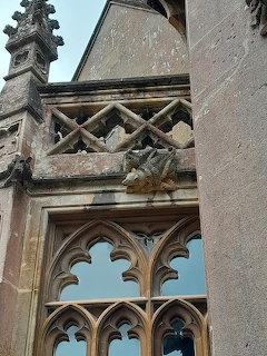 Stone gargoyles on Victorian Gothic window with ornate tracery at Tyntesfield manor