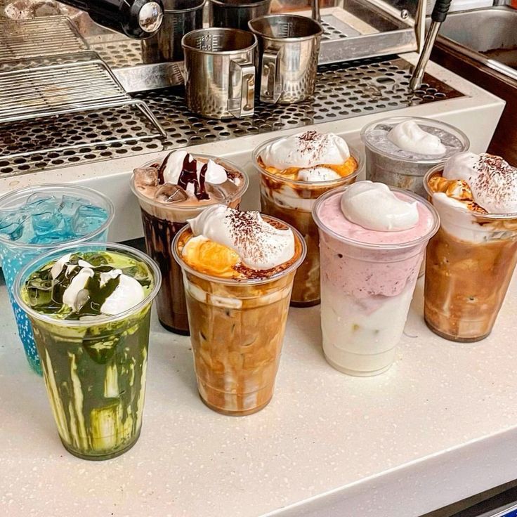 Colorful iced drinks with whipped cream on a cafe counter near an espresso machine