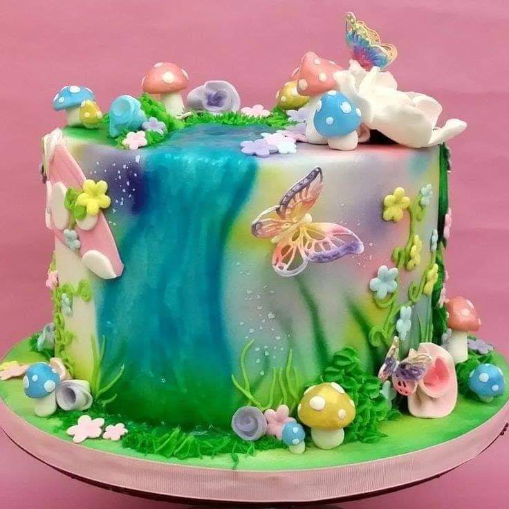 Square cake decorated with watercolor frosting, butterflies, flowers, and pastel eggs on pink surface