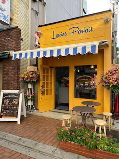 Bright yellow storefront with blue striped awning and outdoor seating