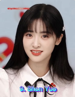 Young Asian woman with long black hair and bangs smiling, wearing a white blouse with black bow tie