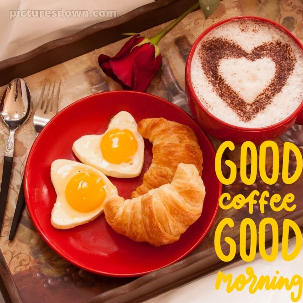 Breakfast tray with heart latte art, croissant and heart-shaped fried eggs on red plate