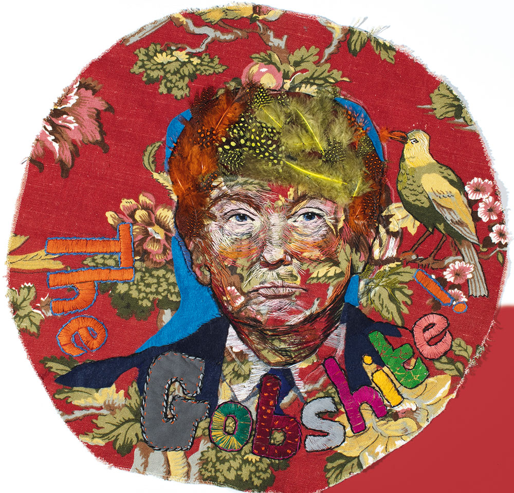 Circular embroidery art with fabric collage portrait, birds, flowers and text on red cloth background