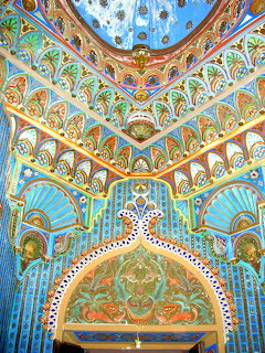 Ornate interior with Moorish arches, intricate geometric patterns in turquoise, gold, and orange covering walls and ceiling