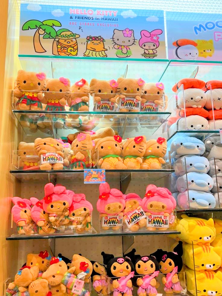 Store shelves filled with Hello Kitty and Sanrio plush toys in Hawaiian-themed costumes and outfits