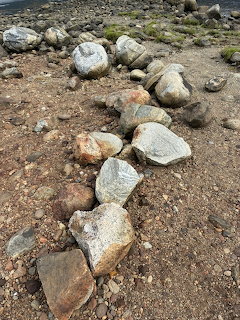 Large rocks arranged in a line on a rocky gravel beach foreshore at Eidfjord, Norway