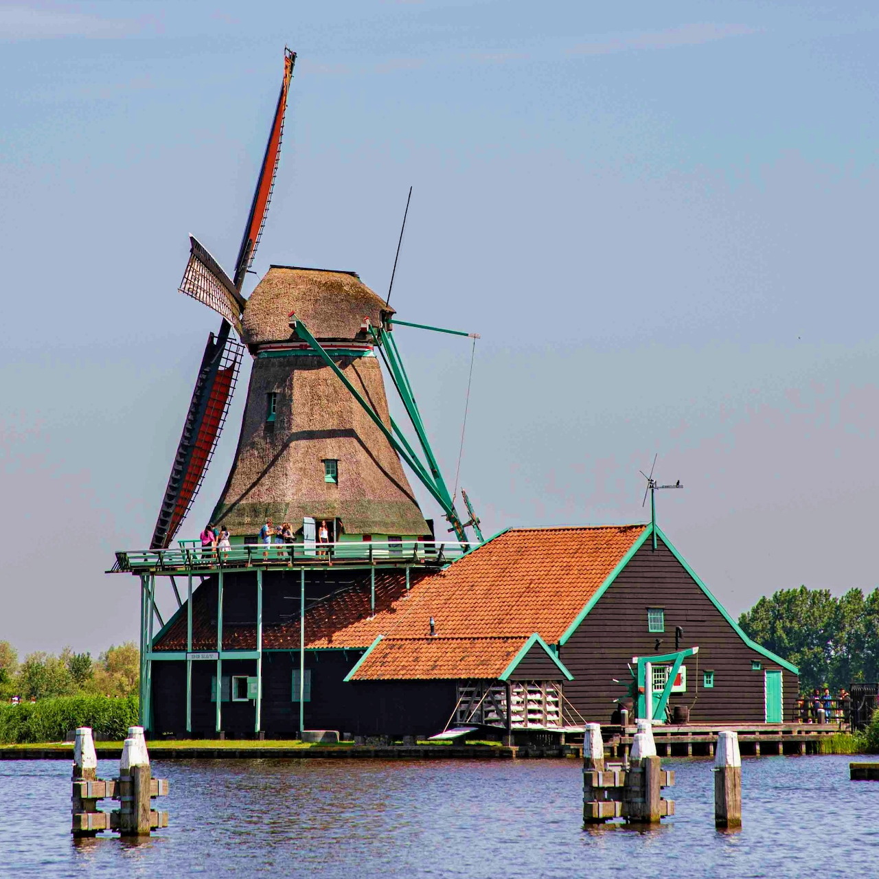 Dutch windmill and house beside a canal under a blue sky