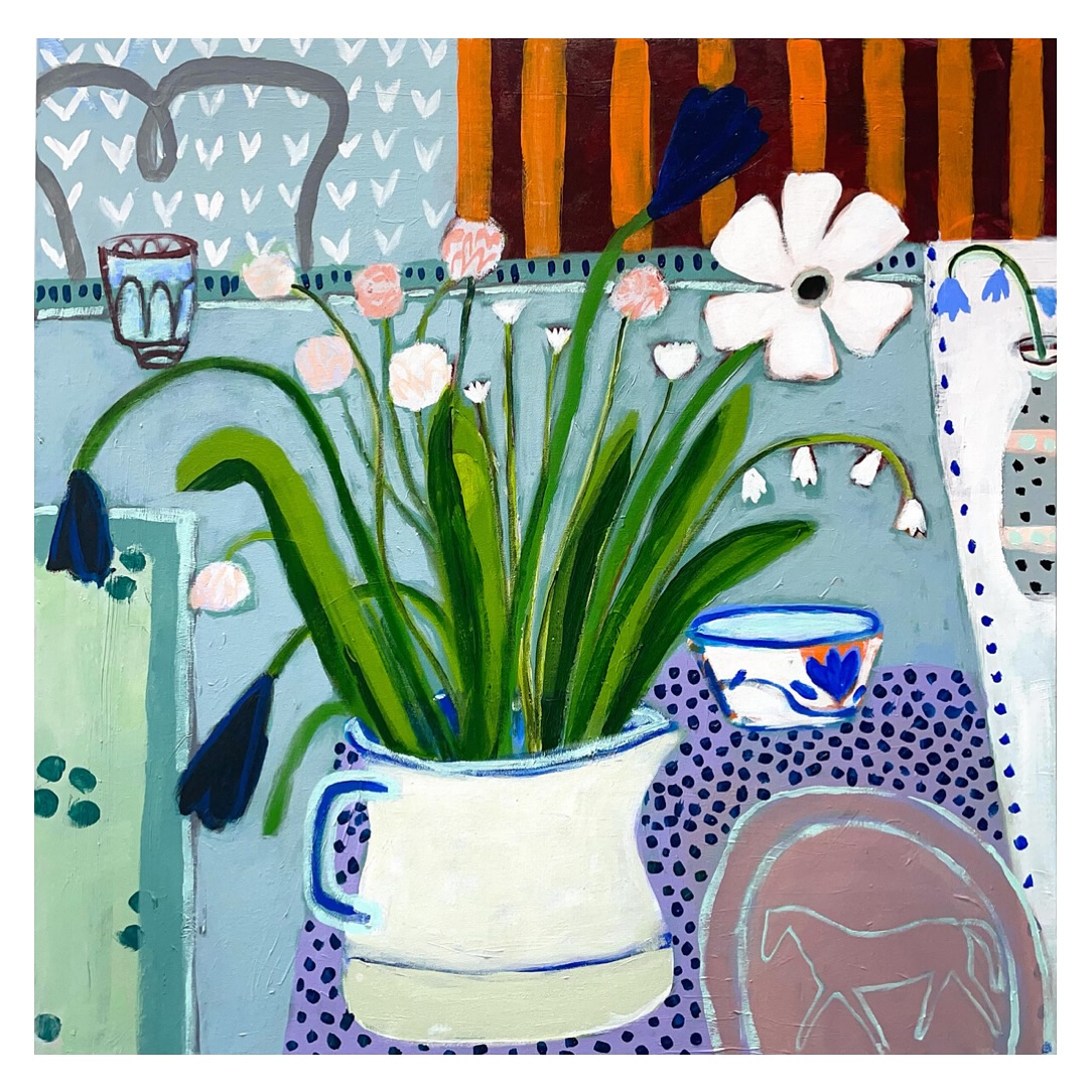 Folk art kitchen scene with white flowers in blue pottery vase on table with decorative plates and patterned textiles