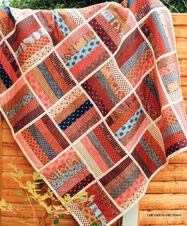 Colorful strip-pieced quilt with diagonal patchwork blocks on wooden floor