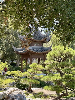 Ornate Japanese pagoda pavilion framed by green trees and garden foliage
