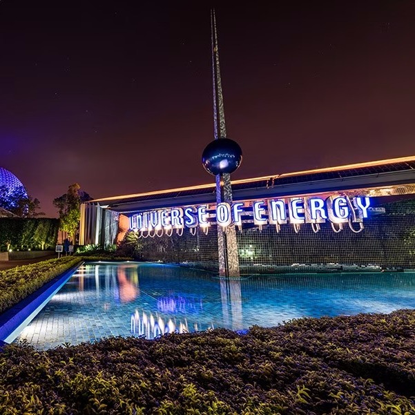 Illuminated Universe of Energy pavilion at Epcot at night with reflecting pool and modern sculpture
