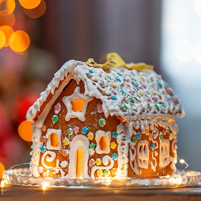 Gingerbread house decorated with icing and candy on a snowy base