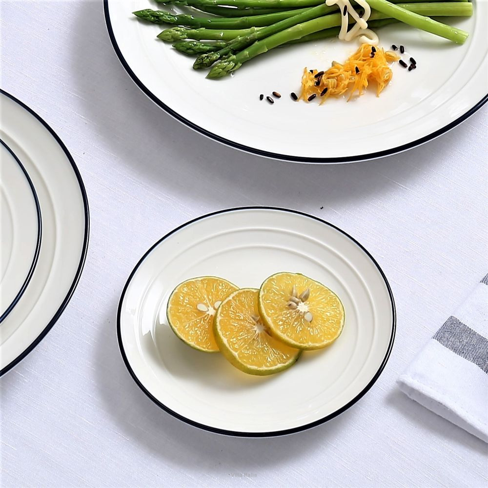 Green asparagus spears and lemon slices arranged on white plates with black rims