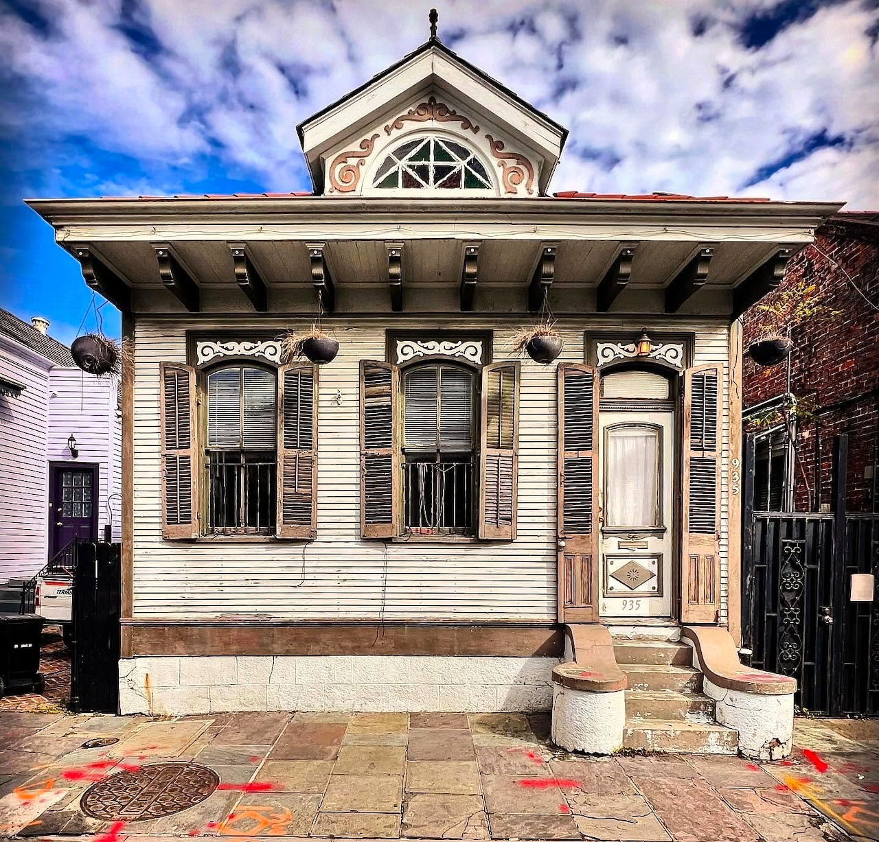 Victorian house with brown ornamental trim and white walls, featuring three tall windows and decorative pediment