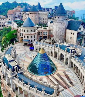 Aerial view of Ba Na Hills castle with stone towers and a blue glass dome courtyard