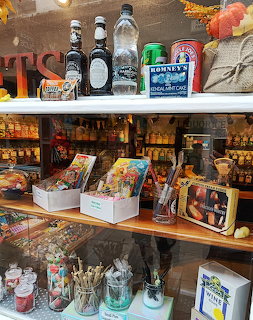 Sweet shop window display with vintage candy tins, glass bottles, and assorted confectionery on wooden shelves