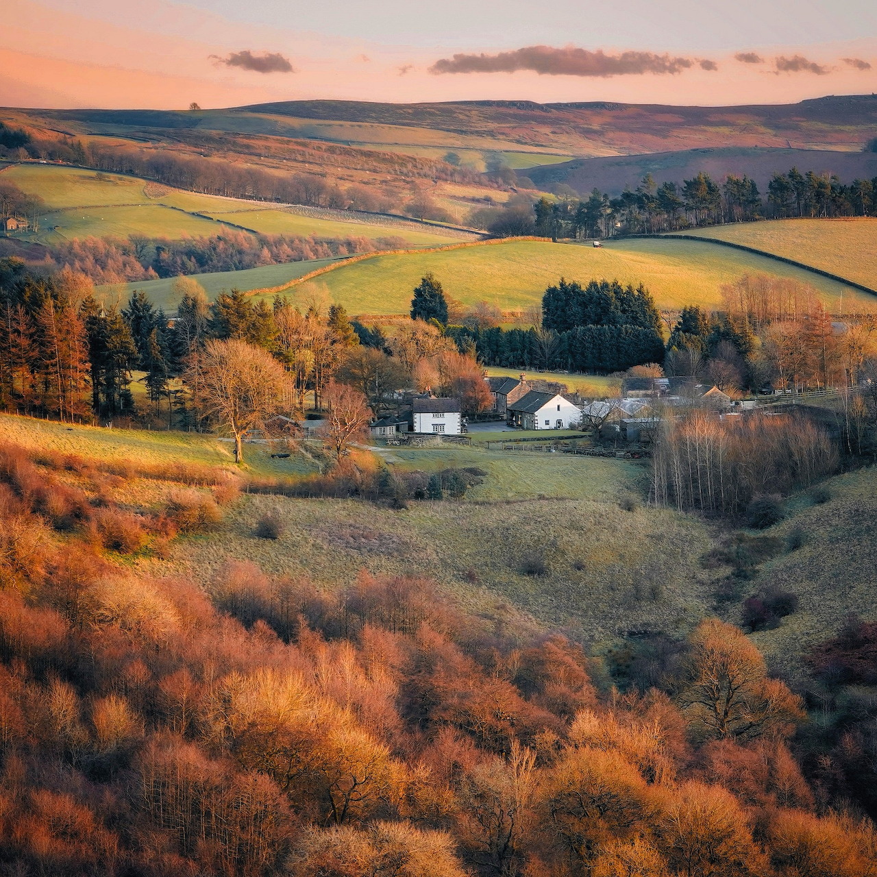 Rolling hills with farmhouses nestled among autumn trees and fields in Peak District landscape