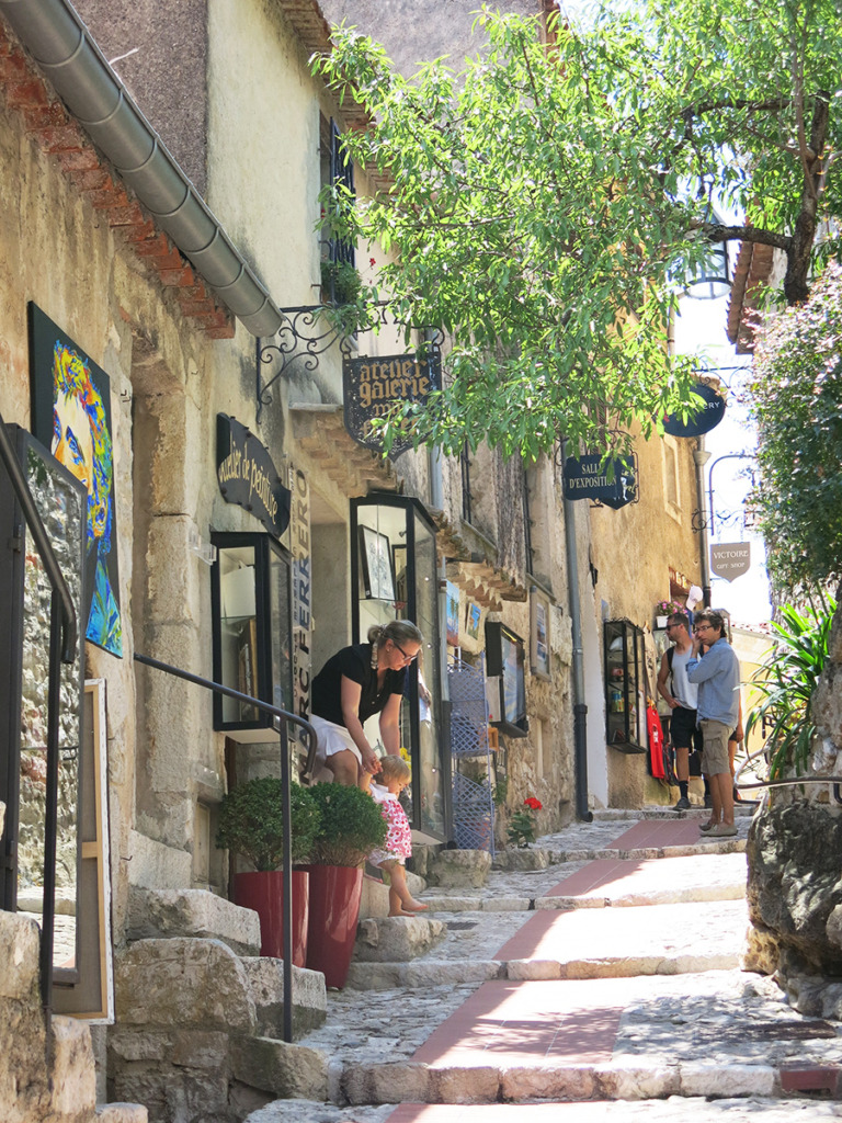 Cobblestone street with stone buildings and art shops in a medieval French village
