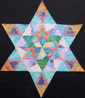 Colorful six-pointed star quilt made of batik fabric triangles in geometric pattern