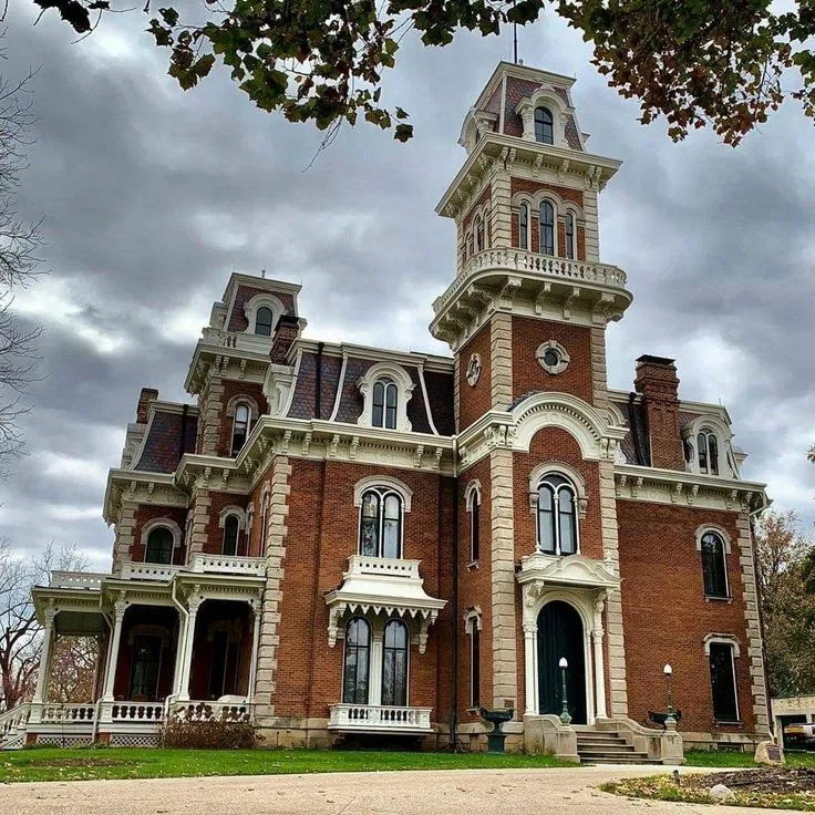 Red brick Victorian mansion with tall clock tower and ornate white architectural details