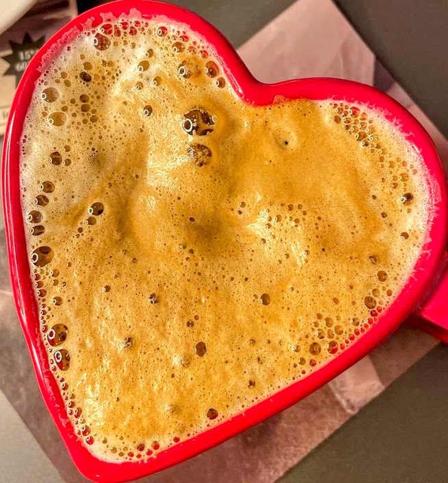 Overhead view of coffee with foam in red heart-shaped mug