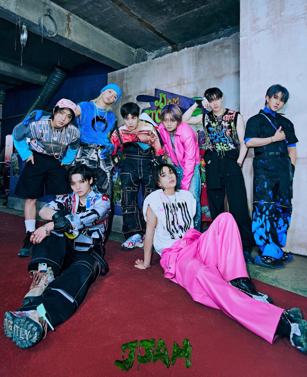 Stray Kids K-pop group of eight members posing together in vibrant outfits with graffiti background