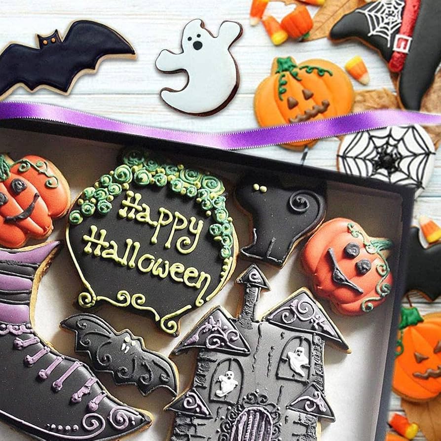Assorted Halloween sugar cookies with orange, black, and white icing arranged on a tray with decorative background