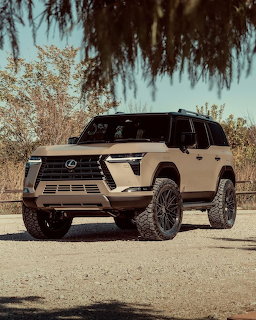Tan lifted Lexus LX SUV with black off-road wheels parked outdoors under tree branches